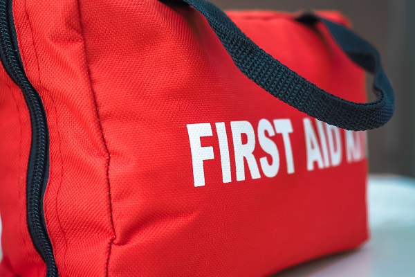 A red first aid kit bag with a black zip and handle, in closeup.